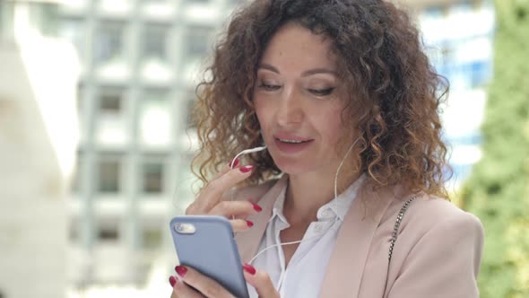 Portrait of a Business Woman Able to Work on a City Street with a Phone and Headphones