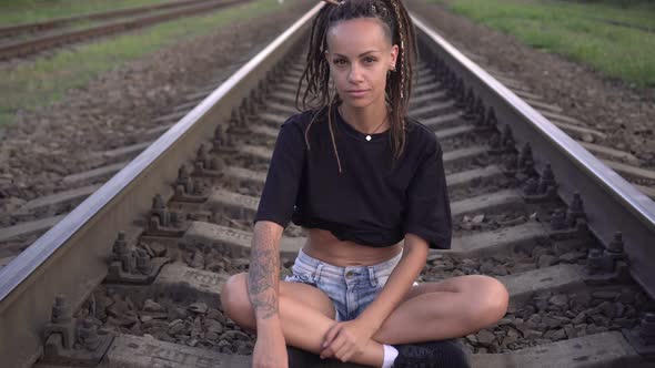 Young Sexy Modern Woman Sits on Rails and Sleepers on the Railroad