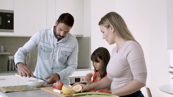 Happy Young Family Couple and Little Girl Cooking Dinner