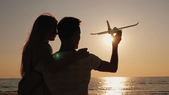 Brother and Younger Sister Play Toy Planes Together on the Beach