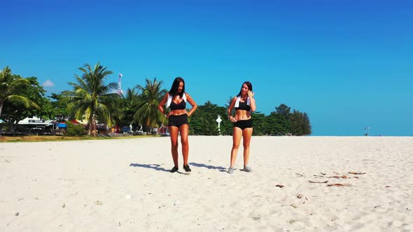 Beautiful women best friends on exotic island beach holiday by turquoise lagoon and white sandy back