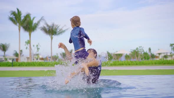 Slowmotion Shot of a Father and Son That Are Having Fun in a Swimming Pool