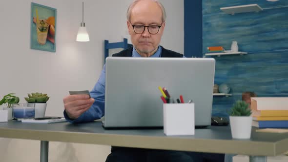 Retired Man Making Shopping Online Doing Payment Using Credit Card on Laptop