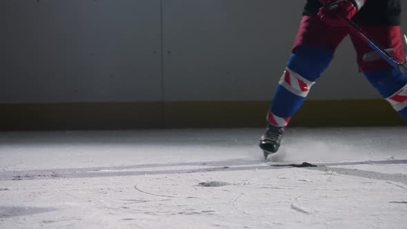 A Hockey Player Slides Across a Dark Ice Arena with Lights Hits the Ice with a Hockey Stick and