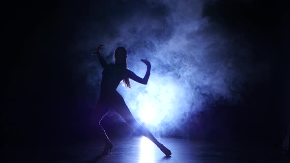 Girl Dancing Movements of Salsa, Rumba, Silhouette. Dark Background, Blue Backlight