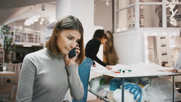 Female Accepting Order From Customer By Cellphone at Sewing Workshop Mixed Race Tailors Taking