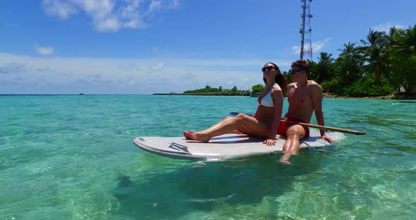 Happy lady and man on honeymoon vacation enjoy luxury on beach on sunny white sandy background