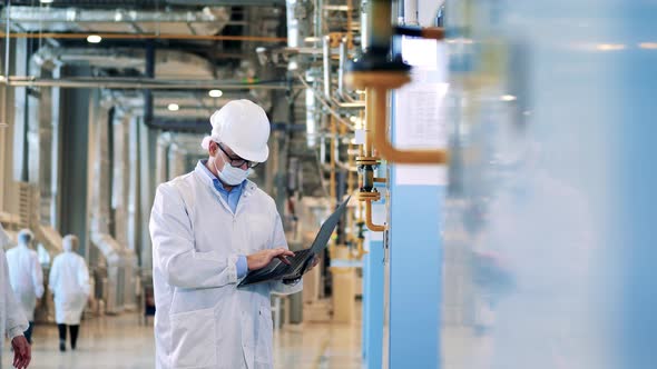 Factory Engineer with a Laptop is Showing Data to His Colleague