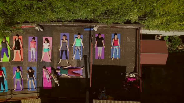 Aerial view of a group of people doing yoga on a terrace surrounded by trees.