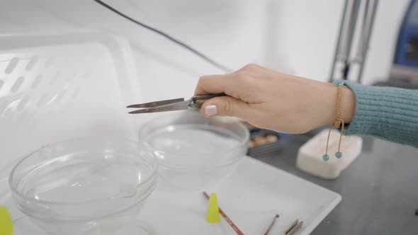 Jeweler With Tweezer Puts Metal Into Crystal Clear Bowl With Liquid In Shop