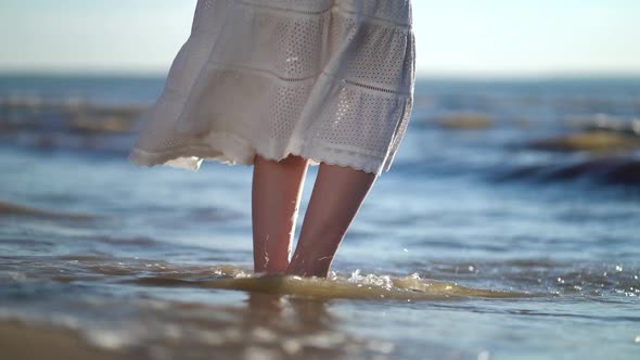 Waves Washing Away Foot at Sunset in the Sandy Beach.