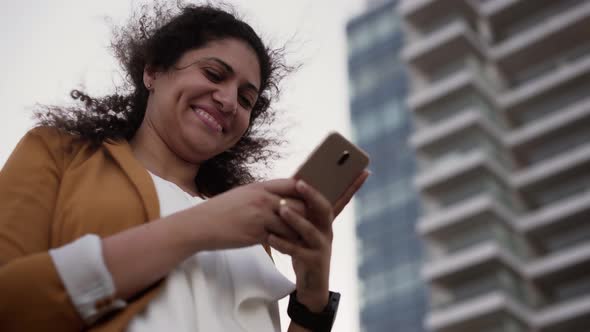 Smiling Young Businesswoman Relaxing on Work Break Texting on Smartphone