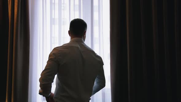 Businessman in luxury room of hotel. Successful businessman looking into window at his hotel