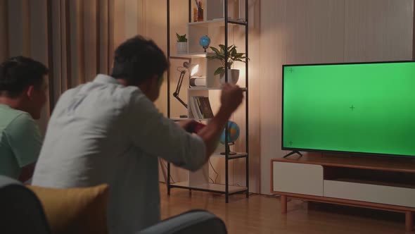 Young Friends With Joystick Game Play Video Game On Green Screen Tv And Celebrating Victory At Home