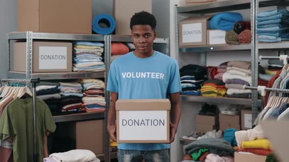 Portrait View of the Multiracial Volunteer Man Holding Box with Clothes for Donation and Looking at