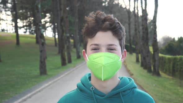 Portrait of a young man in a respiratory mask in the park.