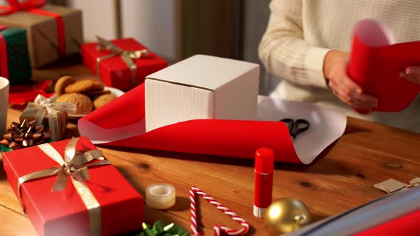 Hands Wrapping Christmas Gift Into Paper at Home
