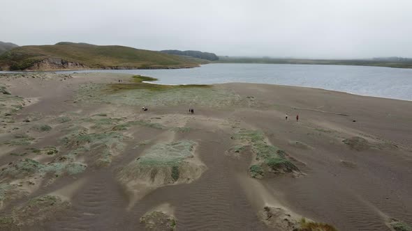 Aerial Fixed Shot Of Campers Exploring Sandy Land Near Blue Calm Sea, California