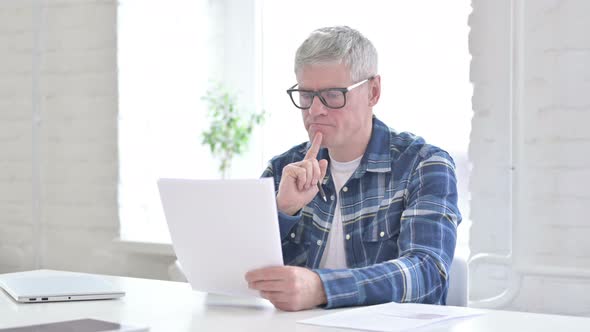 Serious Casual Middle Aged Man Reading Documents in Office