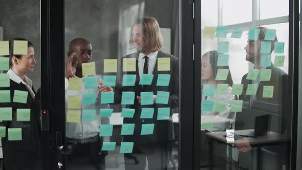 Business Meeting International Management Team at Work Team Is Standing Next To a Glass Board with