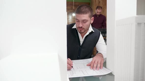 Young Architect Working Near 3D Printed Models of Buildings