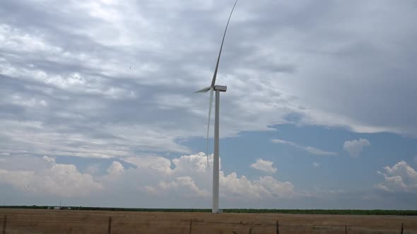 View of windmill spinning while driving past it in slow motion