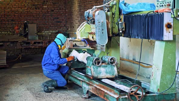 Worker man in special uniform with mask polishing stone in workshop.