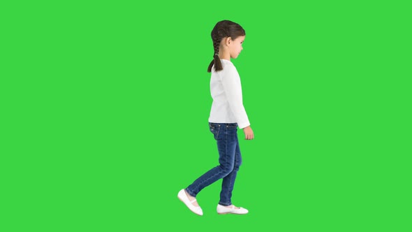 Little Girl with Pig Tails Dressed in White Long Sleeve Top and Jeans Walking on a Green Screen