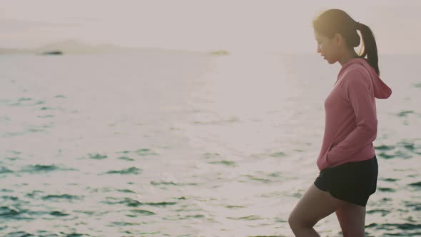 Portrait of young Asian woman walking seaside relaxed enjoying peaceful sunset.