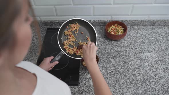 Woman Putting Cooked Fried Rice From Pan Into A Bowl