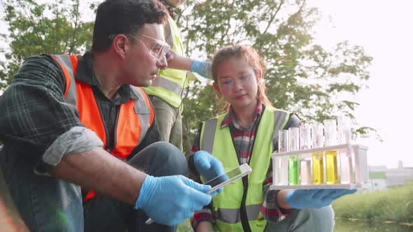 Biological engineer and assistants collecting samples of factory wastewater in a test tube