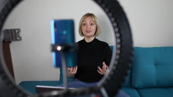 Woman Talking to Camera and Recording Video with Smartphone and Ring Light Lamp at Home Vlogger