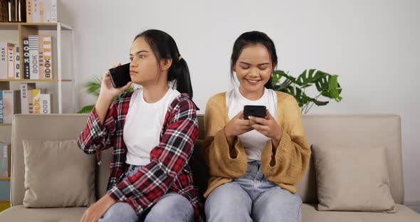 Asian twin girls playing smartphone and talking on phone