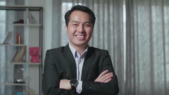 Close Up Of Asian Real Estate Agent Crossing His Arms And Smiling To Camera In The House For Sale