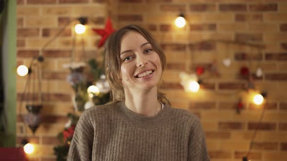 Portrait of Pretty Adult Girl Standing at Home with Christmas Decoration on Background