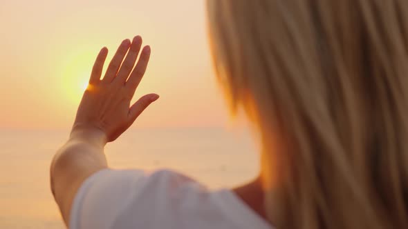 The Woman Extends Her Hand To the Sun Rising Above the Sea. Enjoy the Warmth and Fly of the Concept