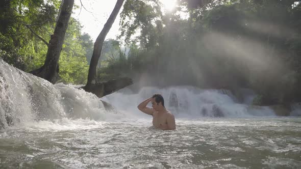 Man Swim With Waterfall And Sunbeams Through Tree