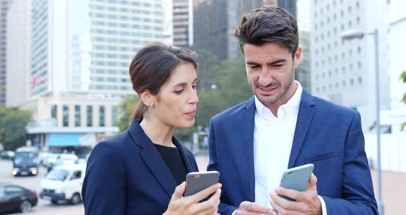 Business people discuss on mobile phone in city
