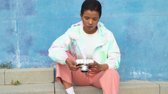 Young woman sitting in front of blue wall taking pictures with camera