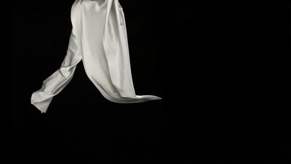 White fabric flowing on black background, Slow Motion alt