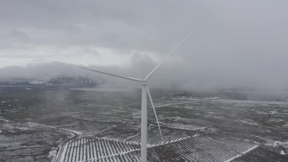 Wind turbine in a snowy landscape with early winter morning mist.