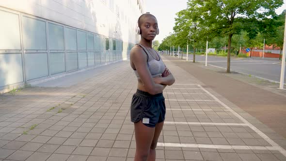 Slow motion shot of young athletic woman with headphones in city