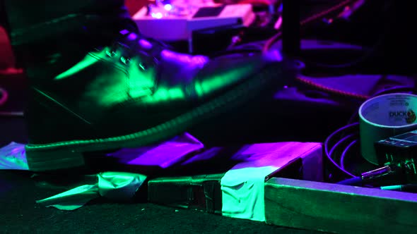 Black boot of guitar player tapping on guitar pedal during performance, close up