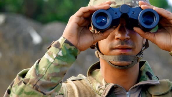 Front view of young caucasian military soldier observing on field during military training 4k
