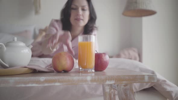 Blurred Caucasian Woman Taking Fresh Apple From Table and Crawling Away on Bed at Home. Happy