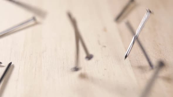 Metallic nails fall in slow motion on a board. Macro shot. Carpenter hardware equipment