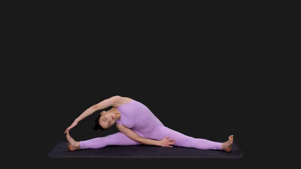 Young Fit Woman Doing Yoga Stretching Exercise Tilts to the Side Sitting on Mat, Alpha in