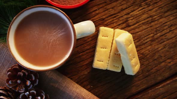 Coffee cup with cocoa powder and cookies on a plank