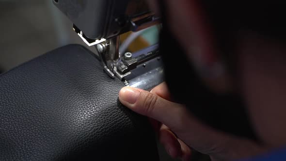 Woman Wearing Face Mask Using Sewing Machine To Sew Zipper On Leather