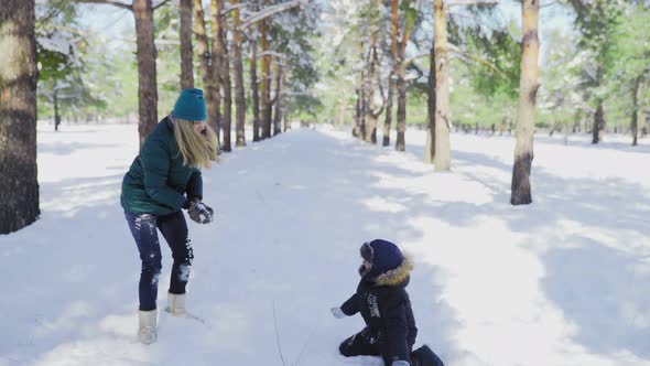 Happy Mother and Son Plays in Snow in Winter Park